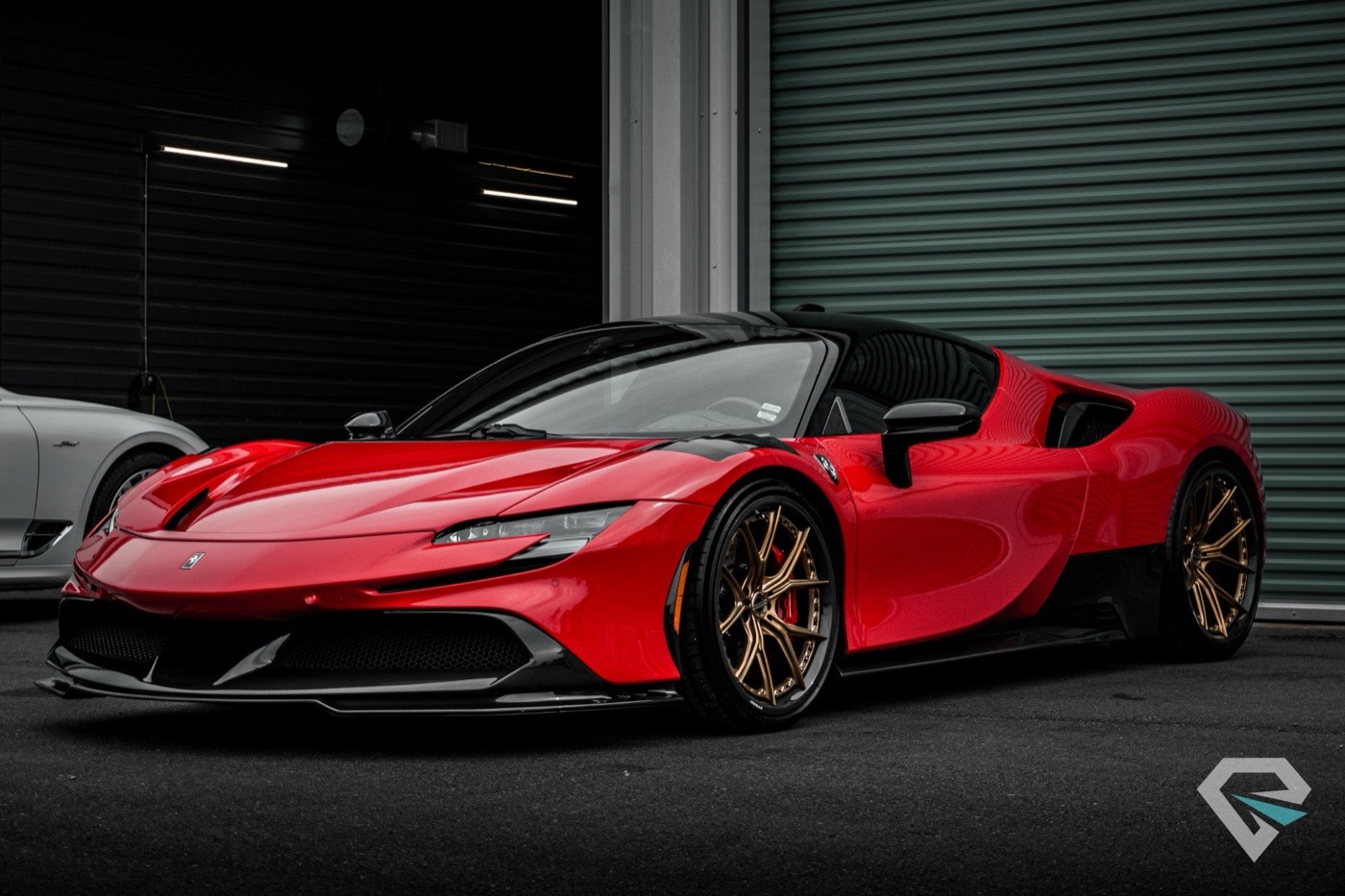 Red Ferrari SF90 parked in the shop, shot low against dark walls